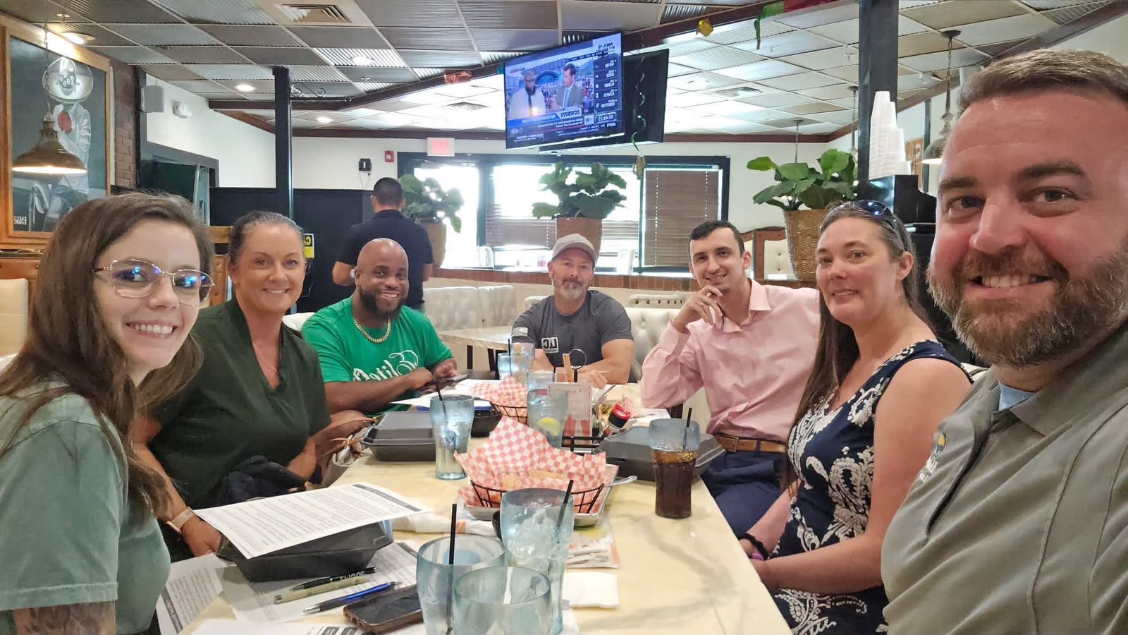 People gathered around a restaurant table, smiling toward the camera